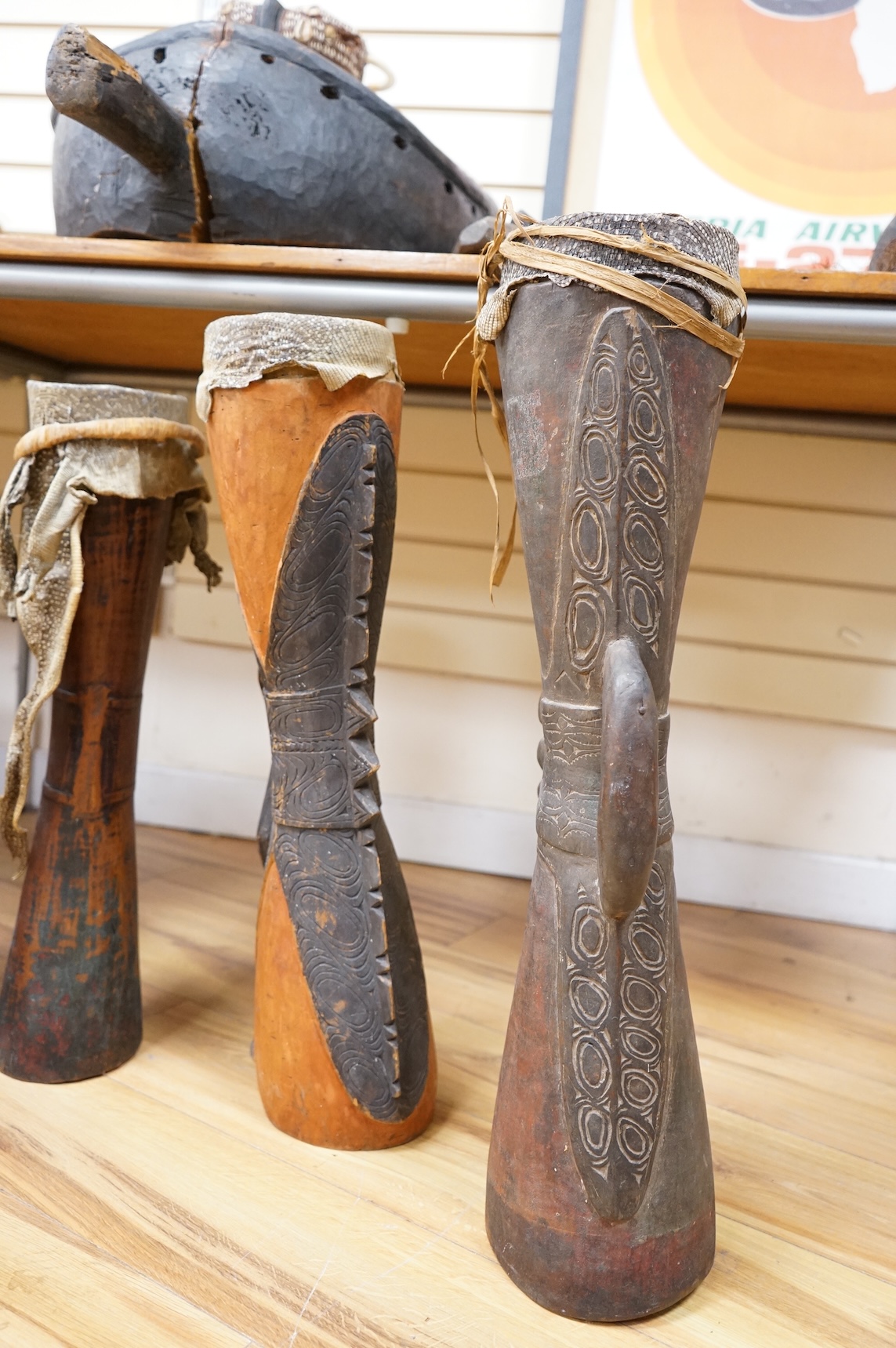 Six Papua New Guinea Sepik River Kundu wooden hand drums, of typical hour-glass form with skin tops, variously carved and incised with two painted, tallest 70cm